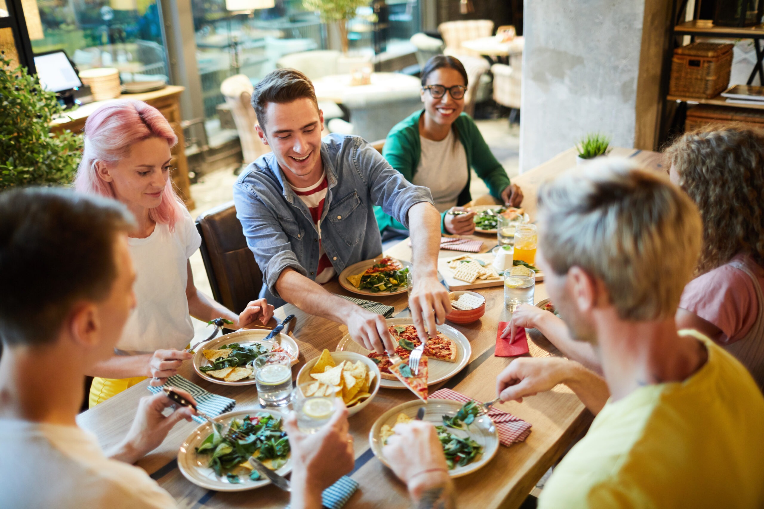 Jeunes au restaurant partageant un repas, discutant de l'utilisation de doggy bags pour éviter le gaspillage alimentaire